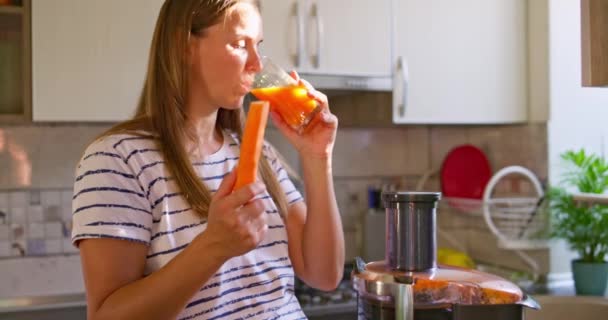 Νεαρή Γυναίκα Πίνει Φρέσκο Χυμό Καρότου Στην Κουζίνα Χάστε Βάρος — Αρχείο Βίντεο