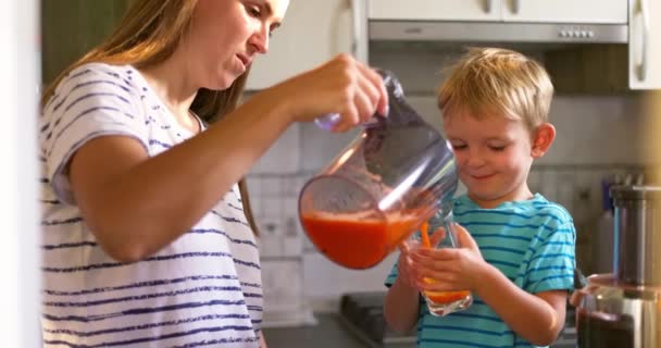 母亲把新鲜榨好的胡萝卜汁倒入杯子里给她的孩子喝 高质量的4K镜头 — 图库视频影像