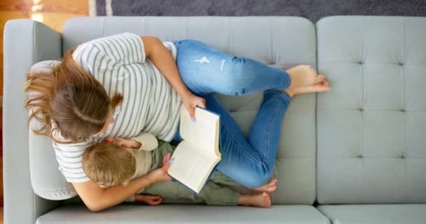 母と息子は 家でソファーに座っている本を読んで一緒に過ごしています 子供の発達と質の高い時間の概念 高品質の4K映像 — ストック動画