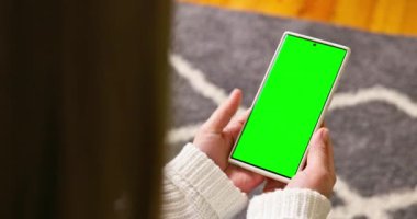 Krom tuşlu, yeşil ekranlı akıllı telefonu tutan esmerin arka planı içeriği izliyor. Kadehler ve çağdaş insanlar konsepti. Yüksek kalite 4k görüntü