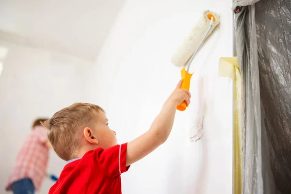 Mother and son are renovating the house - together they paint a wall in the room.