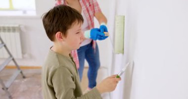 Mutlu bir aile babası ve çocuğu. Duvarı silindir ve fırçayla boyuyor. Apartmanda tamirat var. Yüksek kalite 4k görüntü