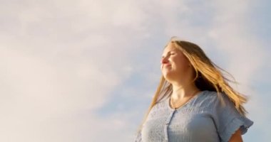 Kaygısız kadın elini kaldırıyor, kendini özgür hissediyor, rahatlıyor, gökyüzü arka planında dönüyor. Özgürlük kavramının tadını çıkar. Yüksek kalite 4k görüntü