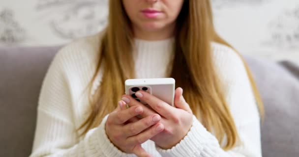年轻女性使用智能手机浏览社交媒体 查看新闻 玩手机游戏或在舒适的沙发上发短信 高质量的4K镜头 — 图库视频影像