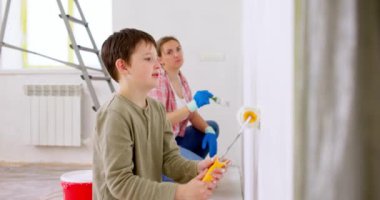 Mutlu bir aile babası ve çocuğu. Duvarı silindir ve fırçayla boyuyor. Apartmanda tamirat var. Yüksek kalite 4k görüntü