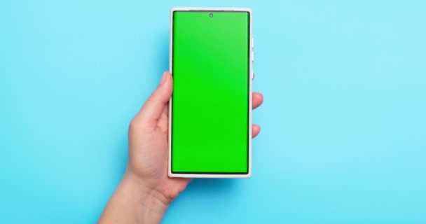 Frauenhände Halten Smartphone Mit Grünem Bildschirm Auf Blauem Hintergrund Hochwertiges — Stockvideo