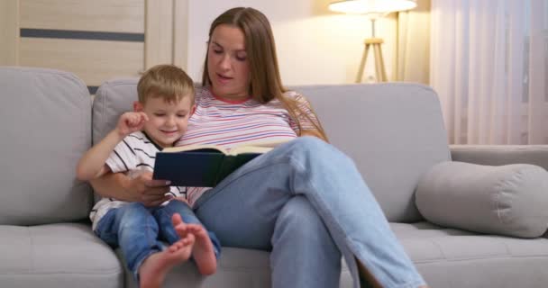 Moeder Zoon Lezen Een Boek Zittend Een Gezellige Bank Woonkamer — Stockvideo