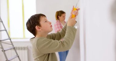 Mutlu bir aile babası ve çocuğu. Duvarı silindir ve fırçayla boyuyor. Apartmanda tamirat var. Yüksek kalite 4k görüntü