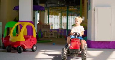 Çocuk pedallı araba kullanıyor, çocuk lunaparkta araba sürerken eğleniyor, çocuk aktiviteleri yapıyor, kapalı alanlarda, kapalı alanlarda. Yüksek kalite 4k görüntü