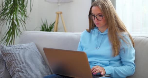 Νεαρή Γυναίκα Που Κάθεται Στον Καναπέ Χρησιμοποιώντας Laptop Κοιτάζοντας Μήνυμα — Αρχείο Βίντεο