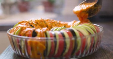Cam kasede dilimlenmiş sebzeler sosla doldurulur. Ratatouille yemek hazırlığı. Yüksek kalite 4k görüntü