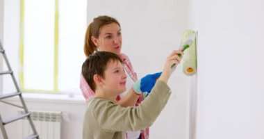 Mutlu bir aile babası ve çocuğu. Duvarı silindir ve fırçayla boyuyor. Apartmanda tamirat var. Yüksek kalite 4k görüntü