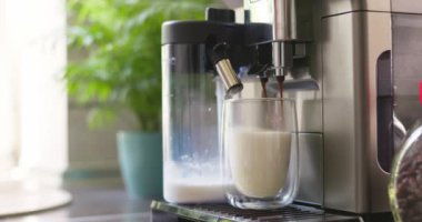 Kahve makinesi kapuçino ya da latte hazırlamak için bir bardak sütlü kahve bardağına espresso koyar. Yüksek kalite 4k görüntü