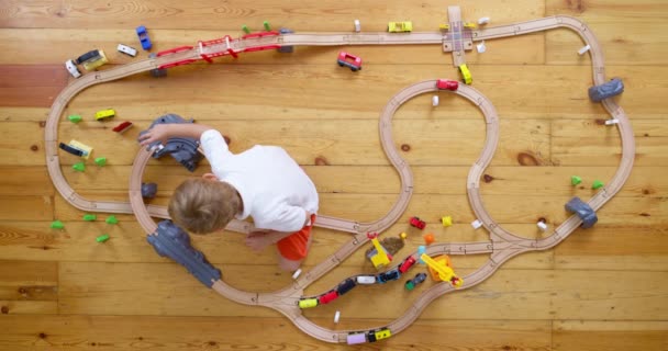 自宅や幼稚園で床に玩具の木製鉄道で遊んでいるかわいい子供 木製の教育玩具 トップビュー 高品質の4K映像 — ストック動画