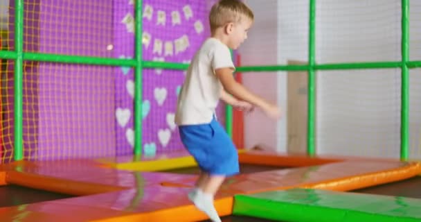 一个孩子在娱乐中心的游乐场里跳踩踏物 活跃的孩子们在操场上玩游戏 高质量的4K镜头 — 图库视频影像