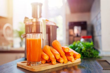 Mutfakta taze sıkılmış havuç suyu, havuç ve meyve sıkacağı var. Sağlıklı yaşam tarzı kavramı