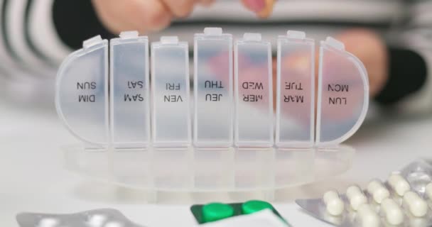 オープンピルオーガナイザーやプラスチック製のピルボックスに丸薬を入れる女性の手 医師の処方に従って毎日の使用のための錠剤のソート — ストック動画