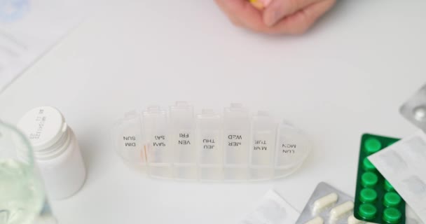 オープンピルオーガナイザーやプラスチック製のピルボックスに丸薬を入れる男性の手 医師の処方に従って毎日の使用のための錠剤のソート — ストック動画