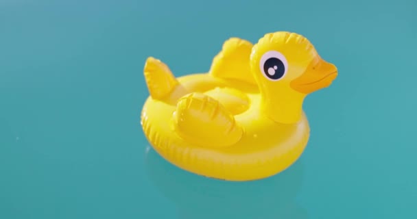 明るい晴れた日に透明な青い水のプールで泳ぐ膨脹可能な黄色のアヒルのおもちゃ 高品質の4K映像 — ストック動画