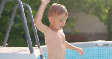 Bahçe bahçesindeki havuza atlayan neşeli çocuk yaz tatilinin tadını çıkarıyor. Büyük bir çerçeve havuzu aile tatili için iyi bir alışveriştir. Yüksek kalite 4k görüntü
