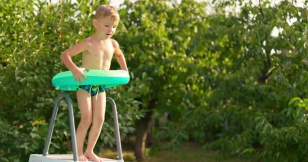 夏休みを楽しんでいる裏庭のプールに飛び込む楽しい少年 大きなフレームプールは 家族の休日のための良い購入です 高品質の4K映像 — ストック動画