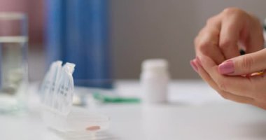 Kadın hapları açık ilaç organizatörüne ya da plastik ilaç kutusuna koyuyor. Doktorların reçetesine göre günlük kullanım için tabletlerin sıralanması