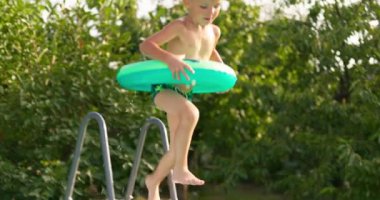 Bahçe bahçesindeki havuza atlayan neşeli çocuk yaz tatilinin tadını çıkarıyor. Büyük bir çerçeve havuzu aile tatili için iyi bir alışveriştir. Yüksek kalite 4k görüntü