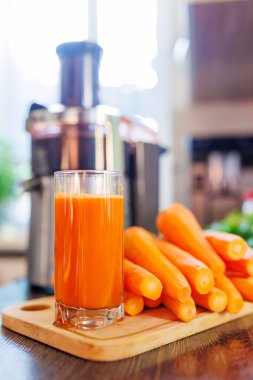 Mutfakta taze sıkılmış havuç suyu, havuç ve meyve sıkacağı var. Sağlıklı yaşam tarzı kavramı