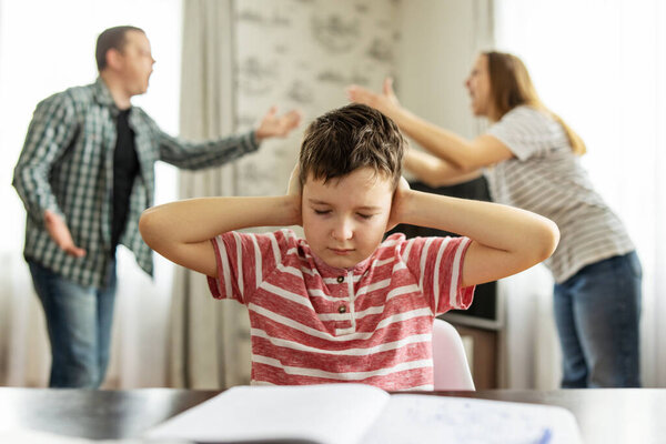 A quarrel between parents in the presence of an upset child covering his ears with his hands. The concept of a family crisis, problems in the family and the need to solve them