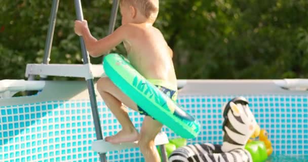 快乐的男孩在后院跳进游泳池 享受暑假 一个大的框架池子是一个家庭度假的好东西 高质量的4K镜头 — 图库视频影像
