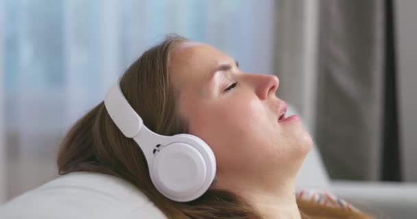 Jovem Relaxante Sofá Confortável Com Olhos Fechados Usando Fones Ouvido — Vídeo de Stock