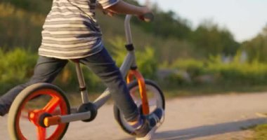 Bir çocuk şehir parkında dengeli bisiklet sürüyor. Bisiklete binen mutlu çocuk, doğada eğleniyor. Aktif aile eğlencesi. Yüksek kalite 4k görüntü