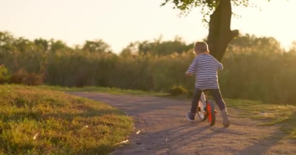 一个男孩在城市公园骑自行车 快乐的男孩骑自行车 在外面玩大自然 积极运动的家庭休闲 高质量的4K镜头 — 图库视频影像