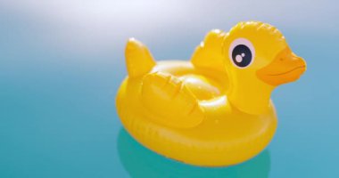Şişme sarı ördek oyuncağı güneşli bir günde berrak mavi su havuzunda yüzer. Yüksek kalite 4k görüntü