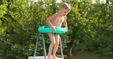 Bahçe bahçesindeki havuza atlayan neşeli çocuk yaz tatilinin tadını çıkarıyor. Büyük bir çerçeve havuzu aile tatili için iyi bir alışveriştir. Yüksek kalite 4k görüntü