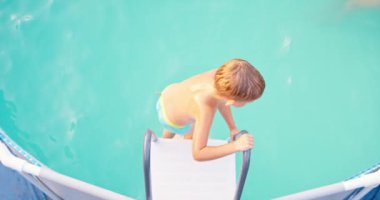Neşeli çocuk havuza atlıyor, havuzda yüzüyor, yaz tatilinin tadını çıkarıyor. Aile yaz tatili. Yüksek kalite 4k görüntü