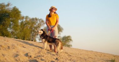 Genç bir kadın yazın evcil köpeğiyle sahilde akşam yürüyüşünden zevk alıyor. Yüksek kalite 4k görüntü