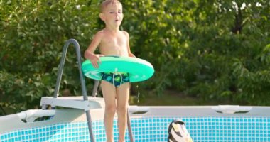 Bahçe bahçesindeki havuza atlayan neşeli çocuk yaz tatilinin tadını çıkarıyor. Büyük bir çerçeve havuzu aile tatili için iyi bir alışveriştir. Yüksek kalite 4k görüntü