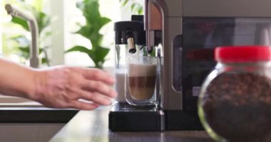 Bir adamın eli bir bardak sıcak kapuçino ya da kahve makinesi tarafından yeni hazırlanmış latte alır. Yüksek kalite 4k görüntü