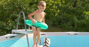 Bahçe bahçesindeki havuza atlayan neşeli çocuk yaz tatilinin tadını çıkarıyor. Büyük bir çerçeve havuzu aile tatili için iyi bir alışveriştir. Yüksek kalite 4k görüntü