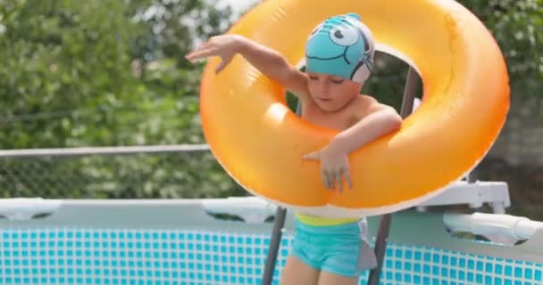 夏休みを楽しんでいる裏庭のプールに飛び込む楽しい少年 大きなフレームプールは 家族の休日のための良い購入です 高品質の4K映像 — ストック動画