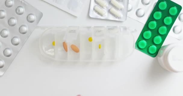 オープンピルオーガナイザーやプラスチック製のピルボックスに丸薬を入れる女性の手 医師の処方に従って毎日の使用のための錠剤のソート — ストック動画