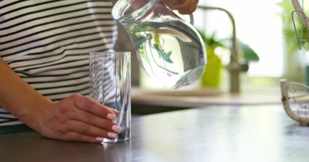 从家里的水壶里把清澈的水倒入杯子里的妇女的近照 高质量的4K镜头 — 图库视频影像