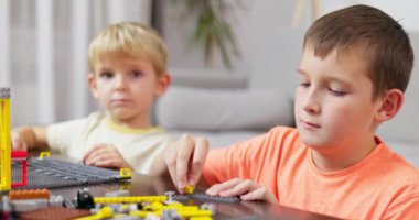 Masada renkli plastik tuğlalarla oynayan ve inşa eden iki çocuk. Erken öğrenme ve geliştirme. Yüksek kalite 4k görüntü