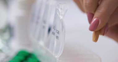 Kadın hapları açık ilaç organizatörüne ya da plastik ilaç kutusuna koyuyor. Doktorların reçetesine göre günlük kullanım için tabletlerin sıralanması