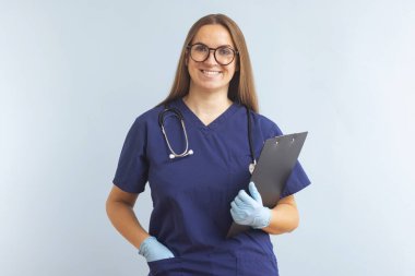 Mavi arka planda gülümseyen ve poz veren gülümseyen kadın doktor portresi. Sağlık ve İlaç Hizmetleri.