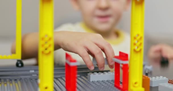テーブルでカラフルなプラスチック製のレンガで遊んで建てている少年 初期の学習と開発 高品質の4K映像 — ストック動画