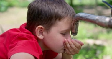 Çocuk dışarıdaki musluktan su içiyor. Yüksek kalite 4k görüntü
