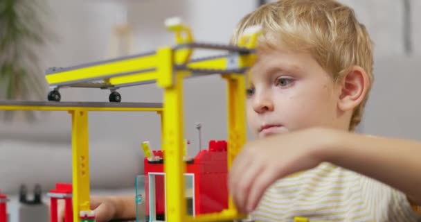 Дитячий Хлопчик Грає Будує Столом Різнокольоровими Пластиковими Цеглинами Раннє Навчання — стокове відео