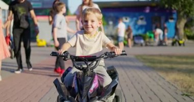 Bir yaz günü parkta oyuncak elektrikli araba kullanan bir çocuk. Bir çocuk elektrikli dörtlü bisiklet sürüyor. Yüksek kalite 4k görüntü